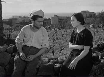 Movie still from “The Earth Trembles” (1948), directed by Luchino Visconti – A man and a woman sitting on a rock wall; Medium shot, High angle