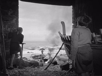 Movie still from “The Earth Trembles” (1948), directed by Luchino Visconti – A black - and - white photo of two people painting a picture; Wide shot, Low angle