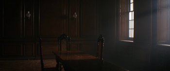 Movie still from “Lady Macbeth” (2016), directed by William Oldroyd – A dark room with a wooden table and two chairs; Wide shot, High angle