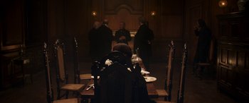 Movie still from “Lady Macbeth” (2016), directed by William Oldroyd – A woman sitting at a dinner table in front of a group of people; Wide shot, High angle