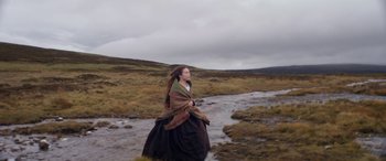 Movie still from “Lady Macbeth” (2016), directed by William Oldroyd – A woman is walking through a field near a stream; Wide shot, High angle