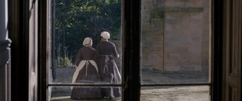Movie still from “Lady Macbeth” (2016), directed by William Oldroyd – Two women dressed in period clothing looking out of a window; Wide shot, High angle