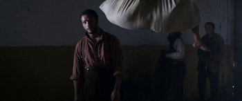 Movie still from “Lady Macbeth” (2016), directed by William Oldroyd – A man standing in a room with a pillow; Medium shot, Low angle