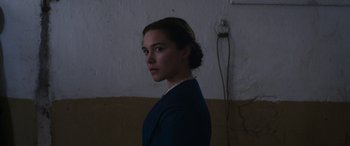 Movie still from “Lady Macbeth” (2016), directed by William Oldroyd – A woman standing in a dark room with her hair in a low bun; Close Up shot, Low angle