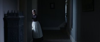 Movie still from “Lady Macbeth” (2016), directed by William Oldroyd – A woman standing in a dark room next to a wall; Medium shot, Low angle