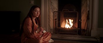 Movie still from “Lady Macbeth” (2016), directed by William Oldroyd – A woman sitting in front of a fire place; Medium shot, Over the shoulder angle