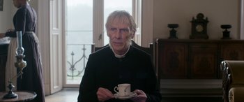 Movie still from “Lady Macbeth” (2016), directed by William Oldroyd – An older man holding a coffee cup in his hands; Close Up shot, Low angle