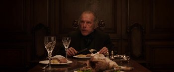 Movie still from “Lady Macbeth” (2016), directed by William Oldroyd – An older man sitting at a dinner table with a plate of food; Medium shot, Over the shoulder angle