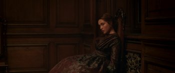 Movie still from “Lady Macbeth” (2016), directed by William Oldroyd – A woman in a dress sitting in a chair; Medium shot, Low angle