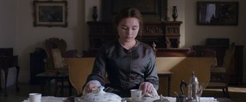 Movie still from “Lady Macbeth” (2016), directed by William Oldroyd – A woman sitting at a table with a bowl of food; Medium shot, Over the shoulder angle