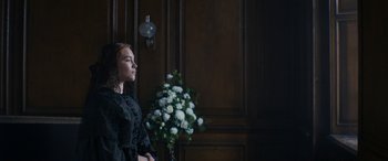 Movie still from “Lady Macbeth” (2016), directed by William Oldroyd – A woman in a black dress standing in front of flowers; Medium shot, Over the shoulder angle