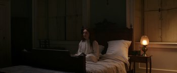 Movie still from “Lady Macbeth” (2016), directed by William Oldroyd – A woman sitting on a bed in front of a laptop; Wide shot, High angle
