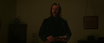Movie still from “Lady Macbeth” (2016), directed by William Oldroyd – A man in a black coat holding a wooden object; Medium shot, Low angle