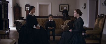 Movie still from “Lady Macbeth” (2016), directed by William Oldroyd – Two women and a little girl sitting on a couch; Medium shot, Over the shoulder angle
