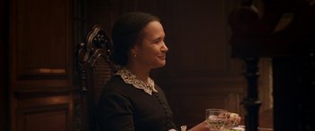 Movie still from “Lady Macbeth” (2016), directed by William Oldroyd – A woman sitting in a chair holding a glass of wine; Medium shot, Over the shoulder angle