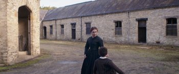 Movie still from “Lady Macbeth” (2016), directed by William Oldroyd – A woman and a boy are walking in the dirt; Wide shot, Over the shoulder angle