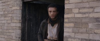 Movie still from “Lady Macbeth” (2016), directed by William Oldroyd – A man standing next to a brick wall; Medium shot, Over the shoulder angle