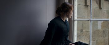 Movie still from “Lady Macbeth” (2016), directed by William Oldroyd – A woman in a black dress looking out a window; Medium shot, Over the shoulder angle