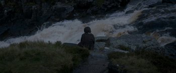 Movie still from “Lady Macbeth” (2016), directed by William Oldroyd – A person sitting on a rock near a river; Extreme Wide shot, High angle