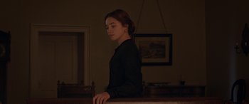 Movie still from “Lady Macbeth” (2016), directed by William Oldroyd – A woman standing in a dark room with her head turned to the side; Medium shot, Low angle