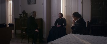 Movie still from “Lady Macbeth” (2016), directed by William Oldroyd – A group of people sitting in a room talking to each other; Medium shot, Over the shoulder angle