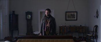 Movie still from “Lady Macbeth” (2016), directed by William Oldroyd – A man standing in front of a mirror in a living room; Medium shot, Low angle