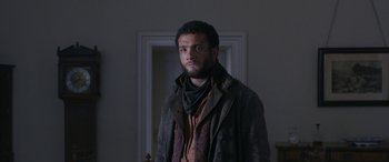 Movie still from “Lady Macbeth” (2016), directed by William Oldroyd – A man standing in front of a door wearing a jacket; Medium shot, Low angle