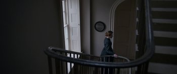 Movie still from “Lady Macbeth” (2016), directed by William Oldroyd – A woman standing on top of a set of stairs next to a window; Wide shot, Low angle