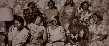 Movie still from “Lady Sings the Blues” (1972), directed by Sidney J. Furie – An old photo of a group of women sitting on a couch; Medium shot, Low angle