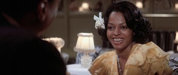 Movie still from “Lady Sings the Blues” (1972), directed by Sidney J. Furie – A woman smiles while sitting at a table; Close Up shot, Over the shoulder angle