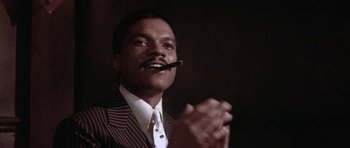 Movie still from “Lady Sings the Blues” (1972), directed by Sidney J. Furie – A man in a suit and tie holding a pipe in his mouth; Close Up shot, Low angle