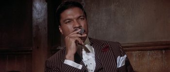 Movie still from “Lady Sings the Blues” (1972), directed by Sidney J. Furie – A man smoking a cigarette while wearing a suit and tie; Close Up shot, Low angle