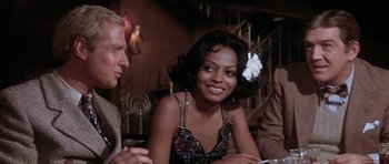 Movie still from “Lady Sings the Blues” (1972), directed by Sidney J. Furie – A woman sitting at a table with two other people; Close Up shot, Over the shoulder angle