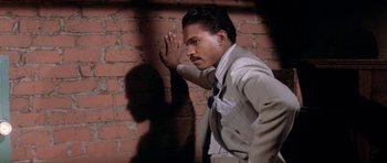 Movie still from “Lady Sings the Blues” (1972), directed by Sidney J. Furie – A man standing in front of a brick wall with his hand up to his face; Close Up shot, Low angle