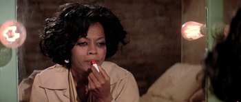 Movie still from “Lady Sings the Blues” (1972), directed by Sidney J. Furie – An older black woman is putting lipstick on her lips; Close Up shot, High angle
