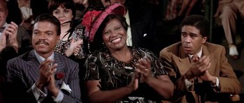 Movie still from “Lady Sings the Blues” (1972), directed by Sidney J. Furie – An older woman wearing a pink hat clapping her hands; Close Up shot, Over the shoulder angle