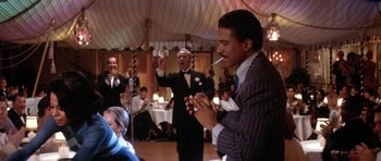 Movie still from “Lady Sings the Blues” (1972), directed by Sidney J. Furie – A man in a suit and tie holding a cigarette and clapping; Medium shot, Over the shoulder angle