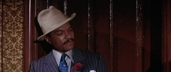Movie still from “Lady Sings the Blues” (1972), directed by Sidney J. Furie – A man wearing a suit and hat with a rose; Close Up shot, Over the shoulder angle