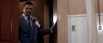 Movie still from “Lady Sings the Blues” (1972), directed by Sidney J. Furie – A man in a suit and tie standing in front of a bathroom door; Medium shot, Low angle