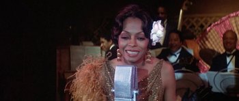 Movie still from “Lady Sings the Blues” (1972), directed by Sidney J. Furie – A person holding a microphone; Close Up shot, High angle