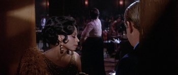 Movie still from “Lady Sings the Blues” (1972), directed by Sidney J. Furie – A woman in a gold dress is talking to another woman in a black dress; Close Up shot, Over the shoulder angle