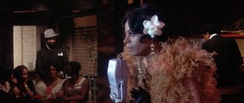 Movie still from “Lady Sings the Blues” (1972), directed by Sidney J. Furie – A woman in a yellow dress is holding a microphone; Close Up shot, Over the shoulder angle