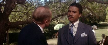 Movie still from “Lady Sings the Blues” (1972), directed by Sidney J. Furie – A man in a suit talks to another man in a suit and tie; Close Up shot, Over the shoulder angle