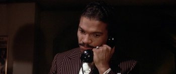 Movie still from “Lady Sings the Blues” (1972), directed by Sidney J. Furie – A man talking on a phone while wearing a suit and tie; Close Up shot, Low angle