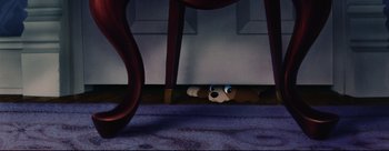 Movie still from “Lady and the Tramp” (1955), directed by Clyde Geronimi – A stuffed dog hiding under a table in a room; Wide shot, High angle
