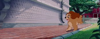 Movie still from “Lady and the Tramp” (1955), directed by Clyde Geronimi – A dog walking on a brick sidewalk in front of a building; Wide shot, Low angle