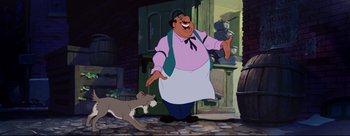 Movie still from “Lady and the Tramp” (1955), directed by Clyde Geronimi – A man and a cat are standing next to each other in front of a building; Medium shot, Low angle
