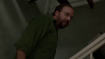 Movie still from “Lady in the Water” (2006), directed by M. Night Shyamalan – A man with a beard and glasses in a green shirt; Medium shot, Low angle