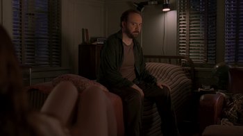 Movie still from “Lady in the Water” (2006), directed by M. Night Shyamalan – A man sitting on top of a couch in a living room; Medium shot, Over the shoulder angle