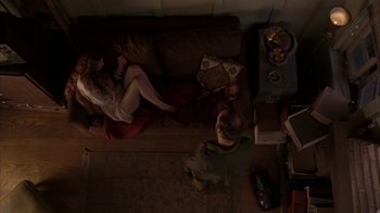 Movie still from “Lady in the Water” (2006), directed by M. Night Shyamalan – Two people sitting on a couch in a living room; Wide shot, Overhead angle